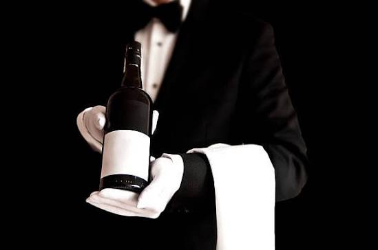 Sommelier in tuxedo presenting wine